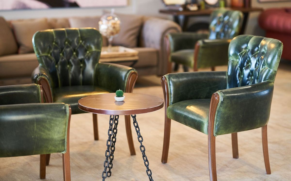 Green leather armchairs with a small round table in a contemporary room