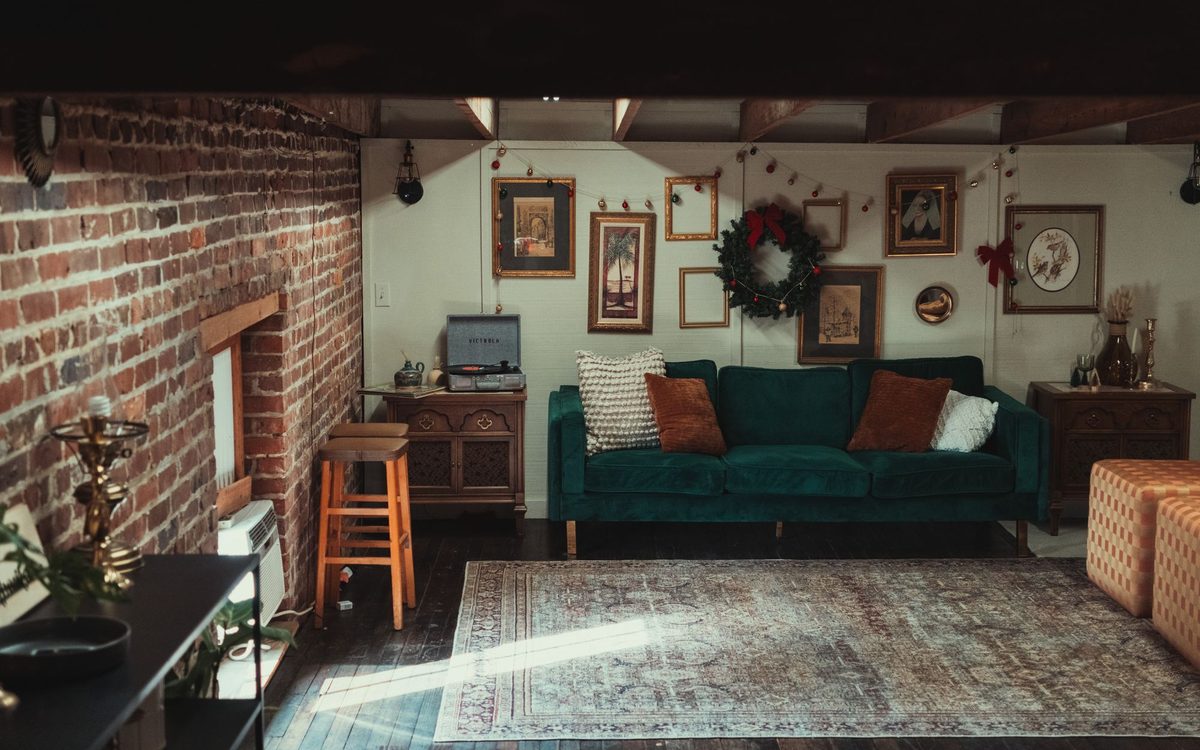 Warm and inviting living room featuring a vintage sofa, brick wall, and artwork display.